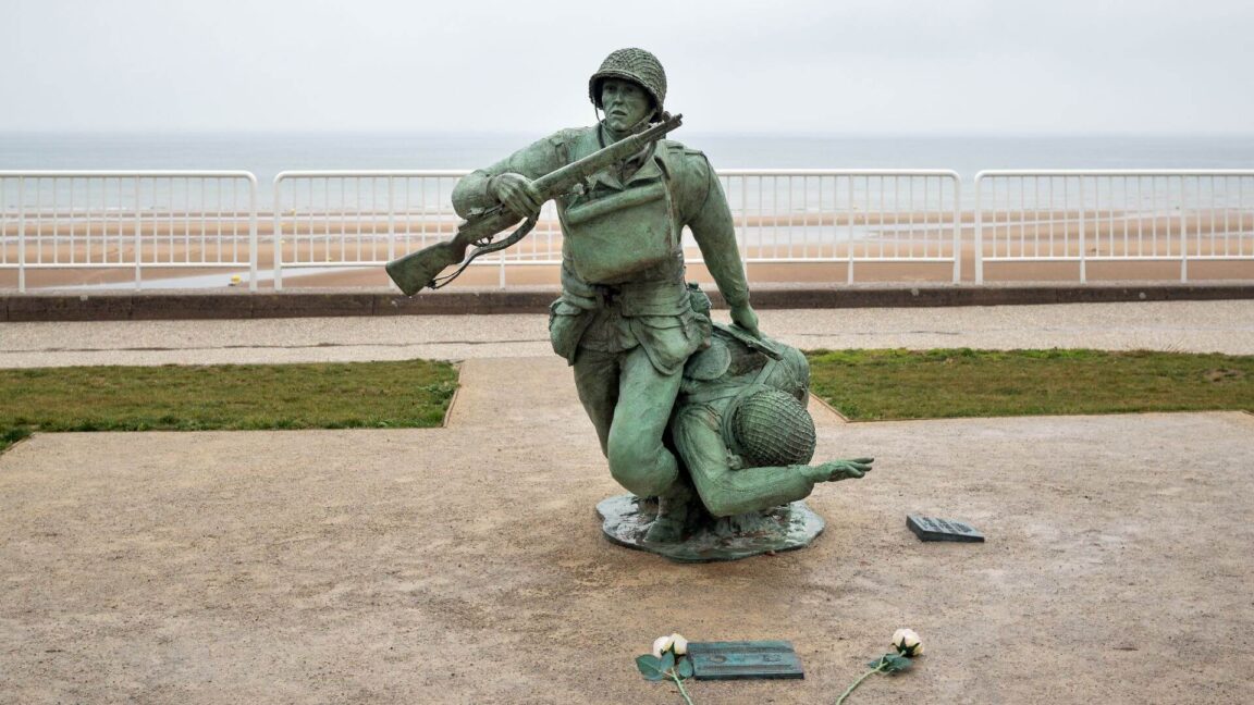 a statue of a soldier dragging a comrade on omaha beach in normandy, france