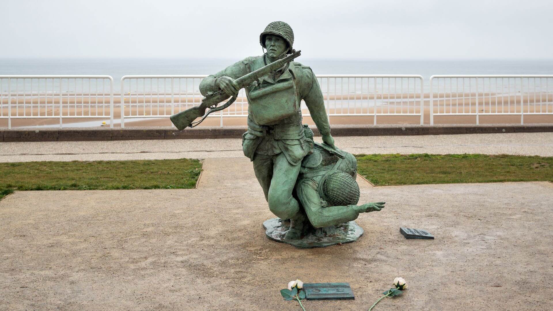 a statue of a soldier dragging a comrade on omaha beach in normandy, france