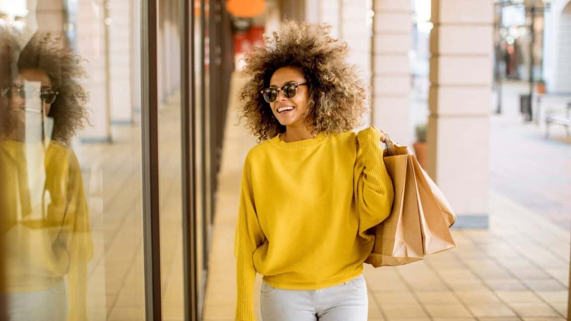 woman in yellow sweater is out shopping at an outdoor mall